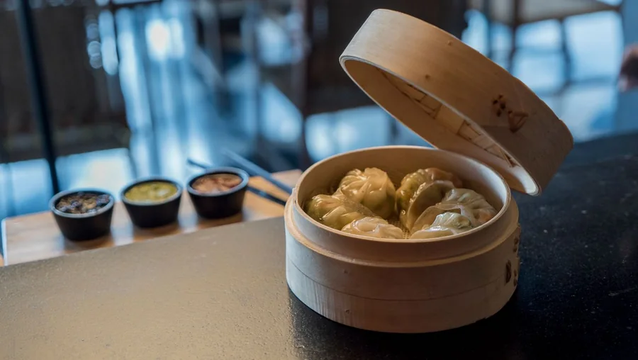 竹蒸笼中的蒸饺与三碟蘸料