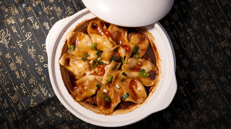 白瓷碗中的馄饨，点缀葱花与红油